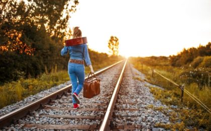 Woman walking along train tracks with a guitar
