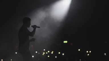 silhouette of a man with a microphone in a spotlight on stage