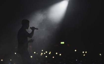 silhouette of a man with a microphone in a spotlight on stage