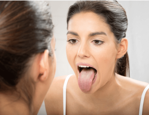 woman looking at her tongue in the mirror