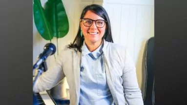 Becky Gilhesbie standing by piano and microphone