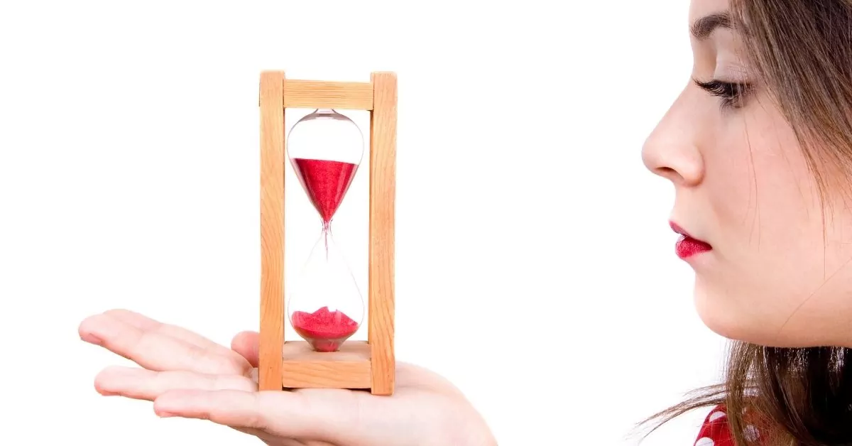 Woman looking at an hour glass in her hand