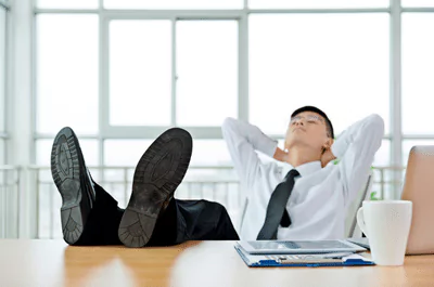feet on desk photo of a man reclined in his chair with his feet on the desk