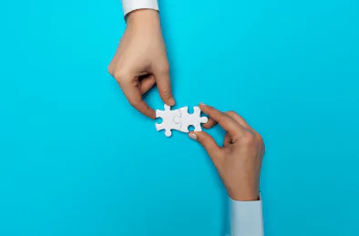 photo of two hands connecting two white puzzle pieces