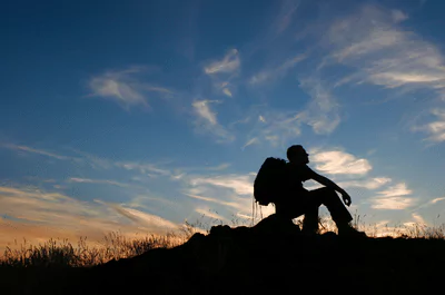 rest photo of a man with a backpack sitting on a rock